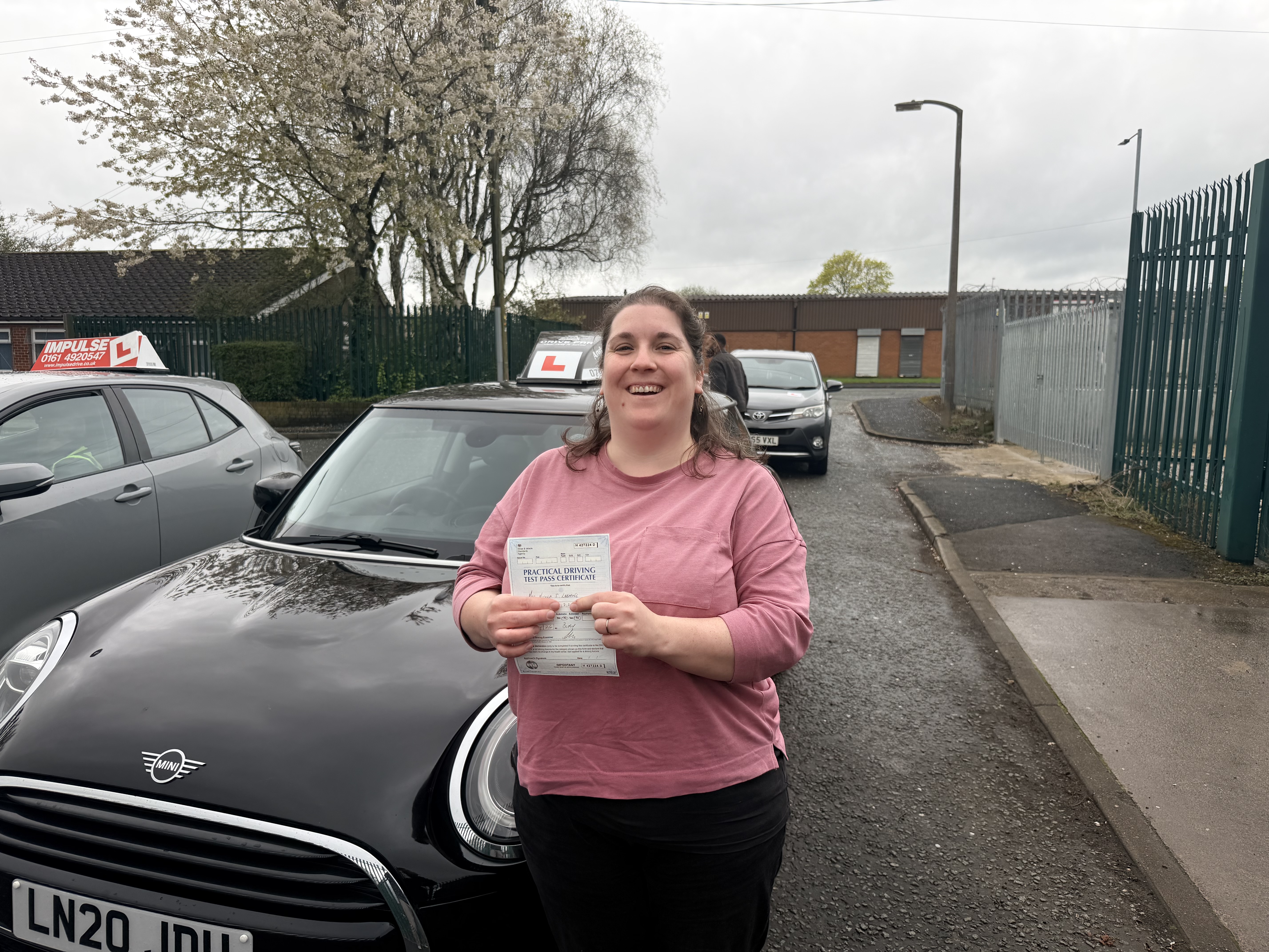 Successful learner holding a practical driving test pass certificate