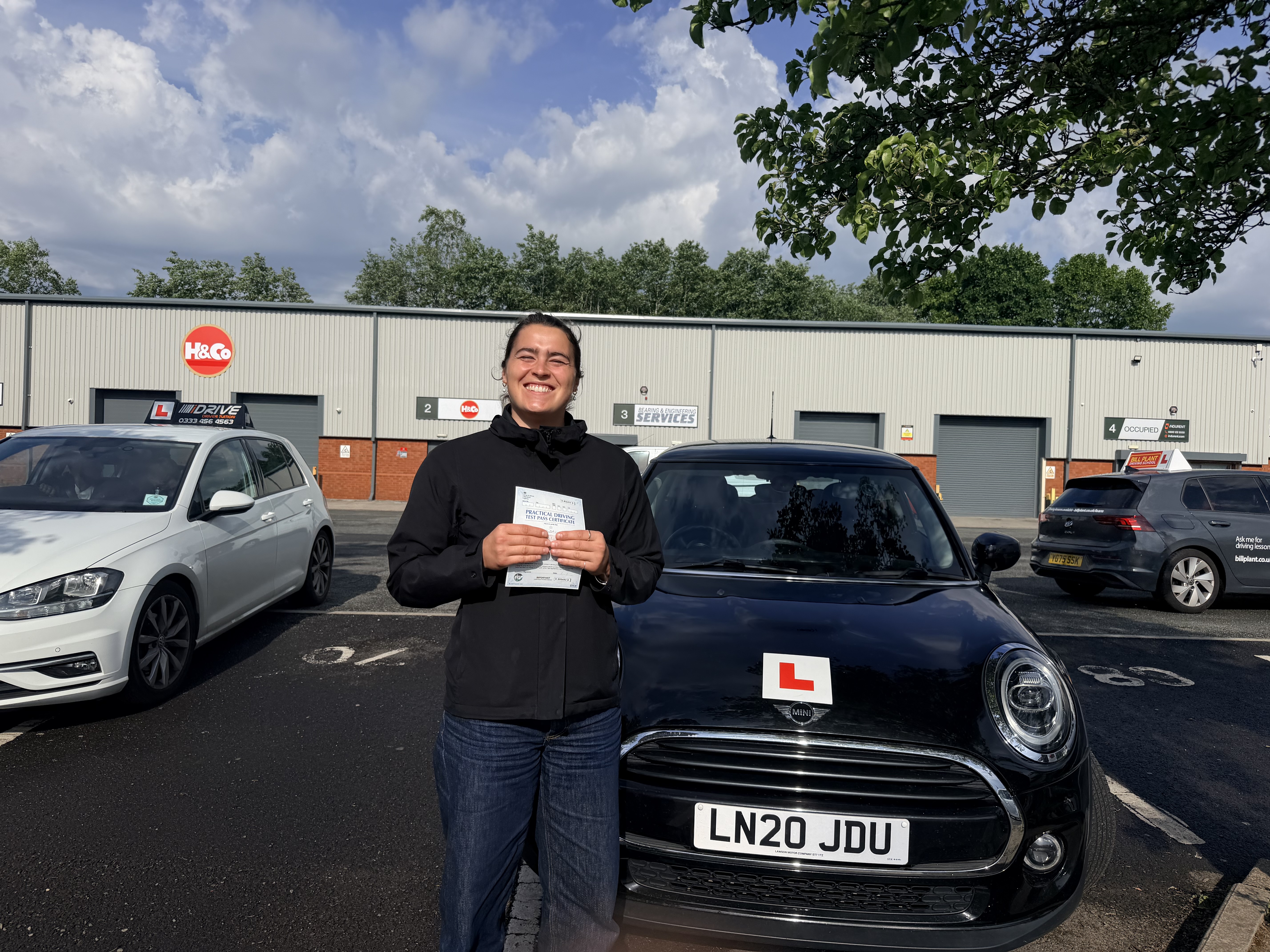 Successful learner holding a practical driving test pass certificate